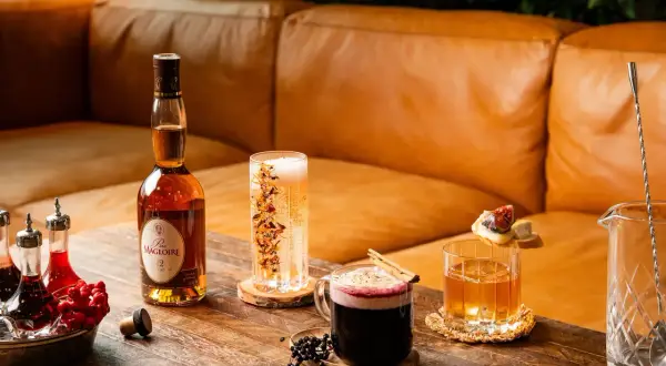 En flaska Calvados, en whisky sour med is och garnityr, en mörk drink med kanel och bär samt en bubblig dryck.