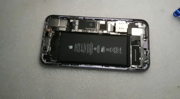 Wnętrze iPhone'a z widoczną baterią i elementami płyty głównej.