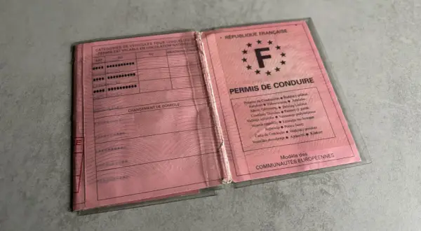Un ancien permis de conduire français, rose, ouvert, montrant les catégories de véhicules et les mentions.