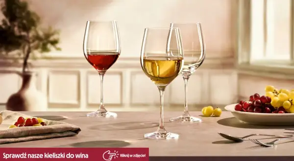 Eleganckie kieliszki do wina, jeden z czerwonym winem, drugi z białym, gotowe na degustacje. Obok winogrona i sztućce.