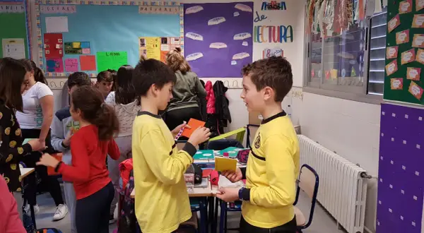 Niños participando en dinámicas de grupo en un aula, interactuando y compartiendo materiales.