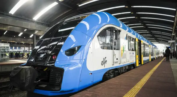 Niebiesko-biały pociąg PKP na peronie. Zastanawiasz się, jak zwrócić bilet PKP kupiony przez internet bez rejestracji? Sprawdź procedury online.