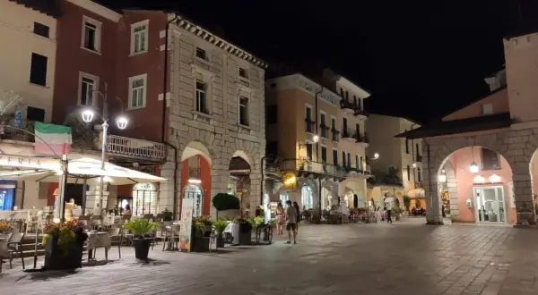 Serata nel centro storico Desenzano del Garda, con locali illuminati e tavolini all'aperto.