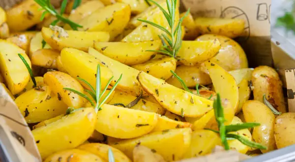Goldgelbe rosmarinkartoffeln vom blech, knusprig und aromatisch, mit frischen Rosmarinzweigen garniert. Ein Genuss für Augen und Gaumen.