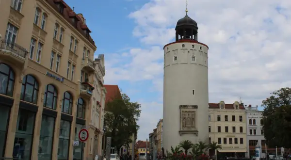 Der Reichenturm dominiert den Marienplatz Görlitz, flankiert von historischen Gebäuden und blühenden Blumenbeeten.