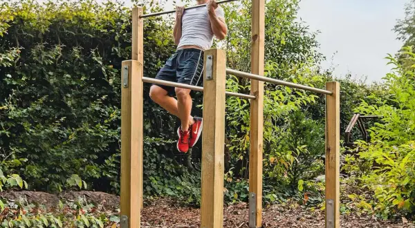 Man tränar pull-ups på ett utegym. Enkla och robusta konstruktioner som inspirerar till att bygga utegym.