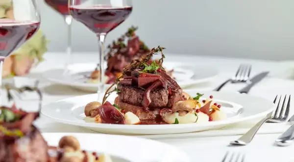 Eleganckie danie z wołowiny z puree i grzybami, podane z czerwonym winem. Zastanawiasz się, ile za talerzyk na wesele?