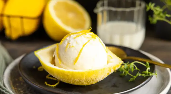 Erfrischendes Buttermilch Zitronen Eis, serviert in einer ausgehöhlten Zitrone, garniert mit Zitronenschale.