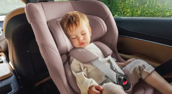 Schlafendes Kleinkind in einer rosafarbenen Babyschale. Die Frage "ab wann sitzschale bei kindern" wird hier durch das Bild beantwortet: ab Geburt.
