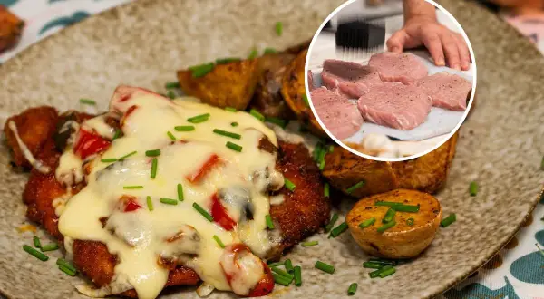 Pyszny kotlet po zbójnicku, zapieczony z serem i warzywami, podany z pieczonymi ziemniakami. W rogu widać surowe mięso do kotleta.