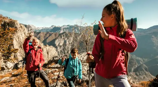 Familia disfrutando de la vista en la montaña, con ropa adecuada para la montaña y equipo de senderismo.