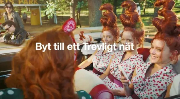 Tre unga kvinnor med fantasifulla frisyrer i en bil. En reklamtext lyder "Byt till ett Trevligt nät".
