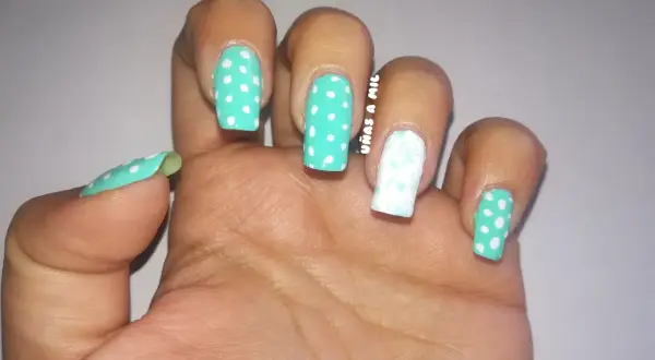 Uñas sevillanas con diseño de lunares turquesa y blanco, y un dedo decorado con un delicado estampado floral.