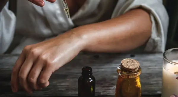 Una persona aplica aceite esencial en su brazo, mostrando cómo usar aceites esenciales para el cuidado de la piel.