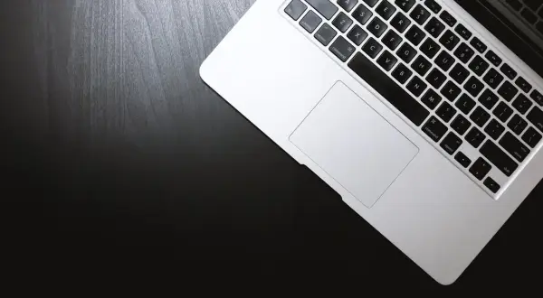 Laptop na czarnym blacie. Dowiedz się, jak otworzyć plik rar, korzystając z klawiatury i touchpada.