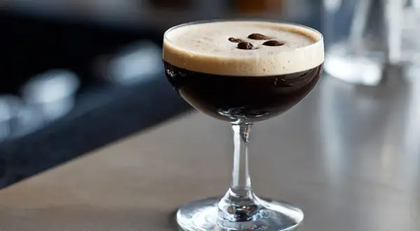 En perfekt espresso martini med krämig skum och tre kaffebönor som dekoration.