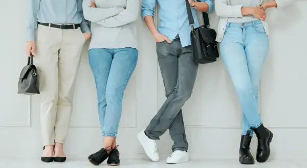 Cztery osoby w stonowanych kolorach, prezentujące styl normcore. Jasne jeansy, beżowe spodnie i szare dżinsy tworzą bazę dla prostych, wygodnych stylizacji.