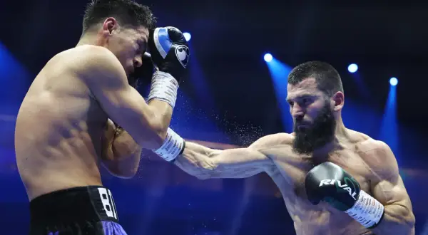 A light heavyweight boxer attempts to block a powerful punch from a heavyweight opponent in a dramatic boxing match.
