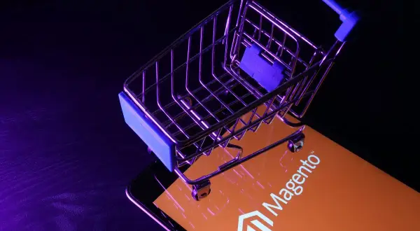 Miniaturowy wózek na zakupy na ekranie z logo Magento, symbolizującym potęgę ecommerce.