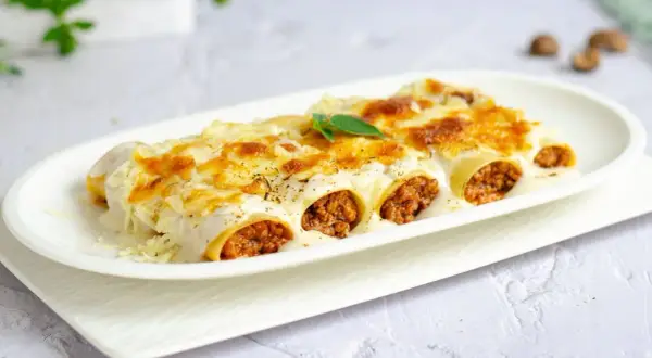 Canelones de carne gratinados, cubiertos con bechamel y queso derretido, listos para disfrutar.