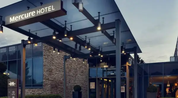 Nowoczesne wejście do hotelu Mercure w Gdańsku, z kamienną fasadą i oświetlonym zadaszeniem.