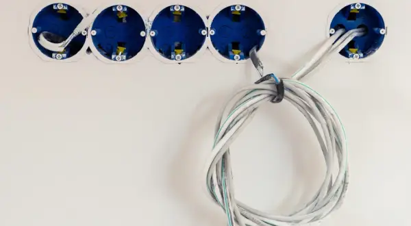 Instalacja elektryczna w trakcie. Widoczne puszki podtynkowe i przygotowane do podłączenia kable. Dowiedz się, jak podłączyć kabel 3 żyłowy do wtyczki.