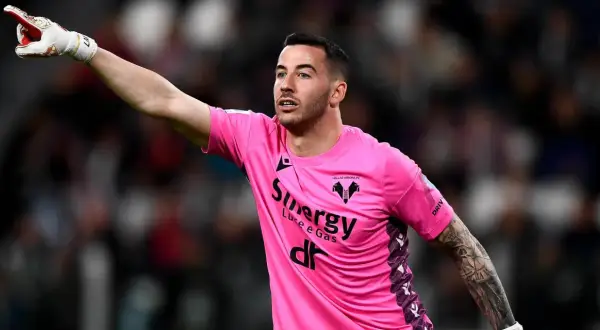 Bramkarz w różowej koszulce Hellas Verona wskazuje palcem, jakby chciał wiedzieć, ile trwa dogrywka w piłce nożnej.
