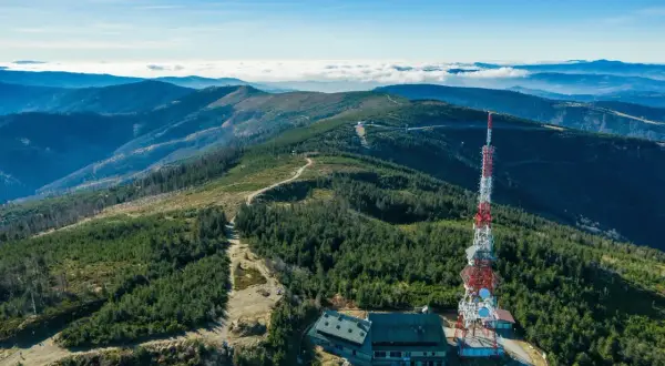 Widok na szczyrk jakie góry, z wieżą telekomunikacyjną i schroniskiem na tle pasm górskich i morza chmur.