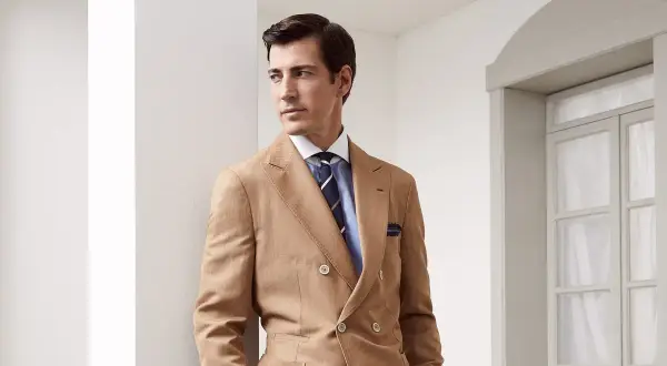 Uomo elegante con abito doppiopetto color cammello e cravatte ultima moda a righe blu.