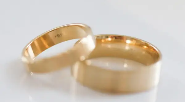Dwie złote obrączki, symbol miłości, z widocznymi zagranicznymi próbami złota.