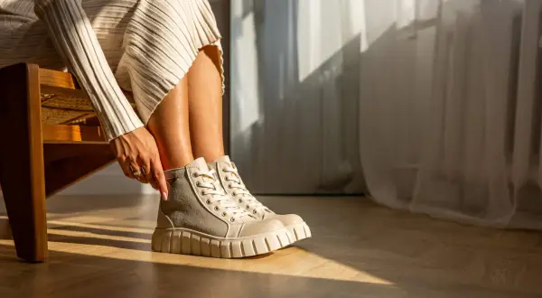 Damskie buty Palladium w beżowo-szarym kolorze na grubej podeszwie, noszone z dzianinową sukienką.