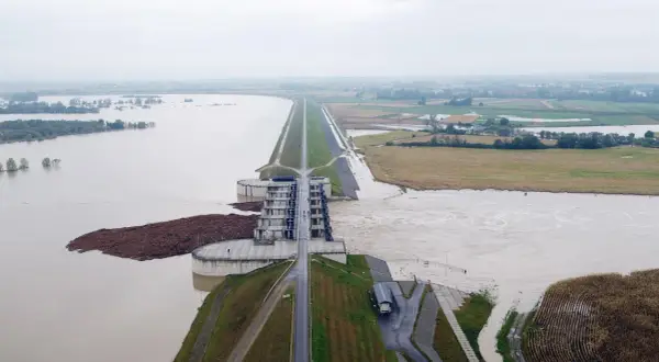 Ogromna tama i budowle hydrotechniczne walczą z żywiołem. Woda sięga pól uprawnych, a w oddali widać zalane tereny. To obraz powodzi błyskawicznej.