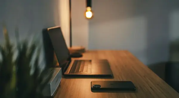 Biurko z laptopem, telefonem i głośnikiem. Idealne miejsce do pracy na pełny etat, gdzie technologia wspiera kreatywność.