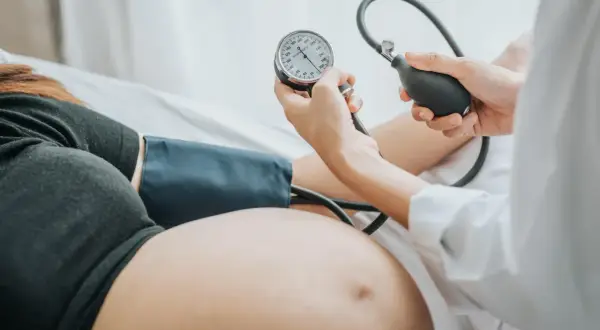 Lekarz mierzy ciśnienie w ciąży u ciężarnej kobiety. Monitoruje jej zdrowie.