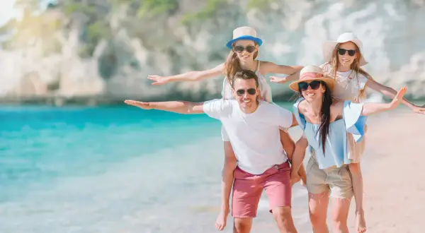 Rodzina na plaży, zastanawiająca się, ile kosztuje ubezpieczenie na wyjazd za granicę.