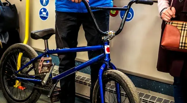 Chłopak z niebieskim rowerem BMX w autobusie, gotowy do podróży.