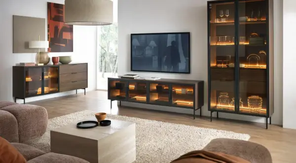 Modernes Wohnzimmer mit gemütlicher Couch. Ein Sideboard und Vitrinenschrank in grau und braun kombinieren, beleuchtet mit warmem Licht.