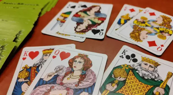 Króle, damy i asy w grach karcianych. Zielona talia kart leży obok.