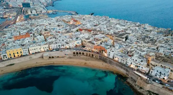 Gallipoli vecchia: un labirinto di vicoli bianchi che si affacciano sul mare turchese, con un'antica muraglia che abbraccia la costa.