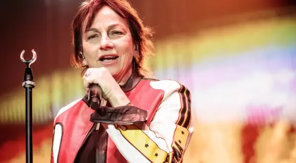 Una cantante con giacca rossa e bianca, microfono in mano, come in un fotoromanzo testo.