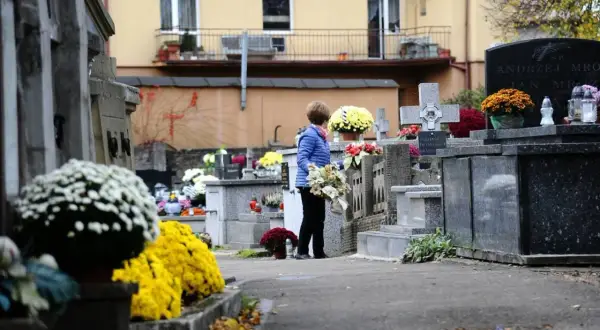 Kobieta z kwiatami na cmentarzu. Warto wiedzieć, jak odszukać groby żołnierskie i miejsca pamięci narodowej, by oddać im cześć.