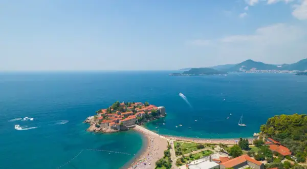 Sveti Stefan, Czarnogóra, gdzie na wakacje? Urokliwa wyspa połączona z lądem, turkusowe morze, plaża pełna ludzi i łodzie. Idealne miejsce na relaks.