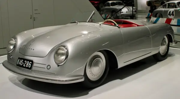 Srebrny kabriolet Porsche 356 z czerwonym wnętrzem, prezentowany na wystawie.
