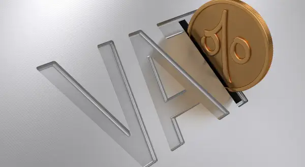 Złota moneta z symbolem procentu wpada do litery "A" w napisie "VAT".
