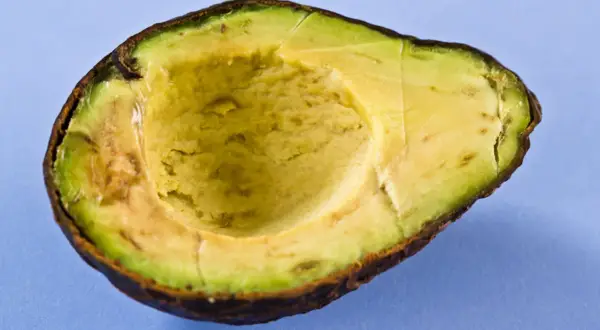 Halbierte Avocado auf blauem Hintergrund. Die Avocado-Wirkung auf die Haut ist bekannt, sie ist reich an Vitaminen und gesunden Fetten.