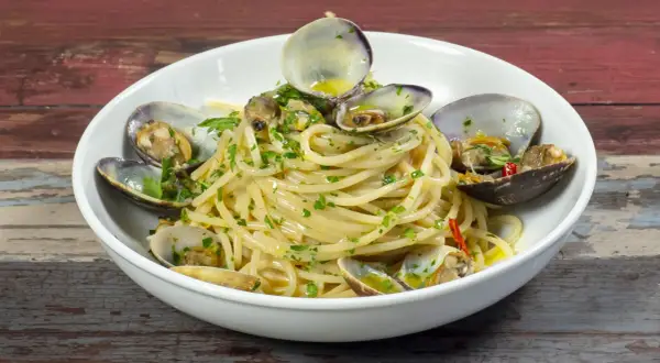 Spaghetti alle vongole, un piatto gustoso con vongole fresche e prezzemolo, pronto per essere gustato.