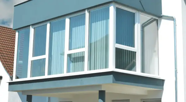 Moderner Anbau mit großen Fenstern, der einen Balkon zum Wintergarten umbauen lässt.