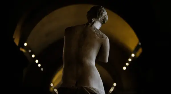 Statue de la déesse de l'amour, vue de dos, dans une lumière tamisée.