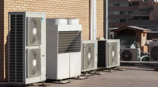 Unidades de aerotermia Repsol en una terraza, junto a un edificio de ladrillo.