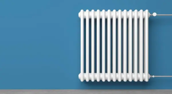 Radiatore bianco su muro blu. Un termotecnico cosa fa? Si assicura che il calore sia distribuito in modo efficiente.